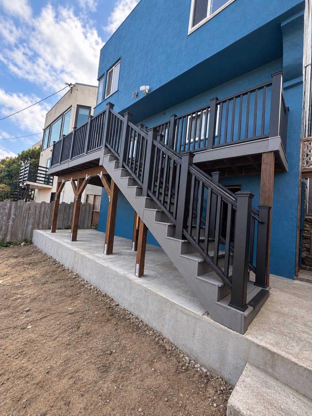 Same home with a new second-story composite deck, braced timber posts, and a composite staircase with black railing built by Gadget Construction