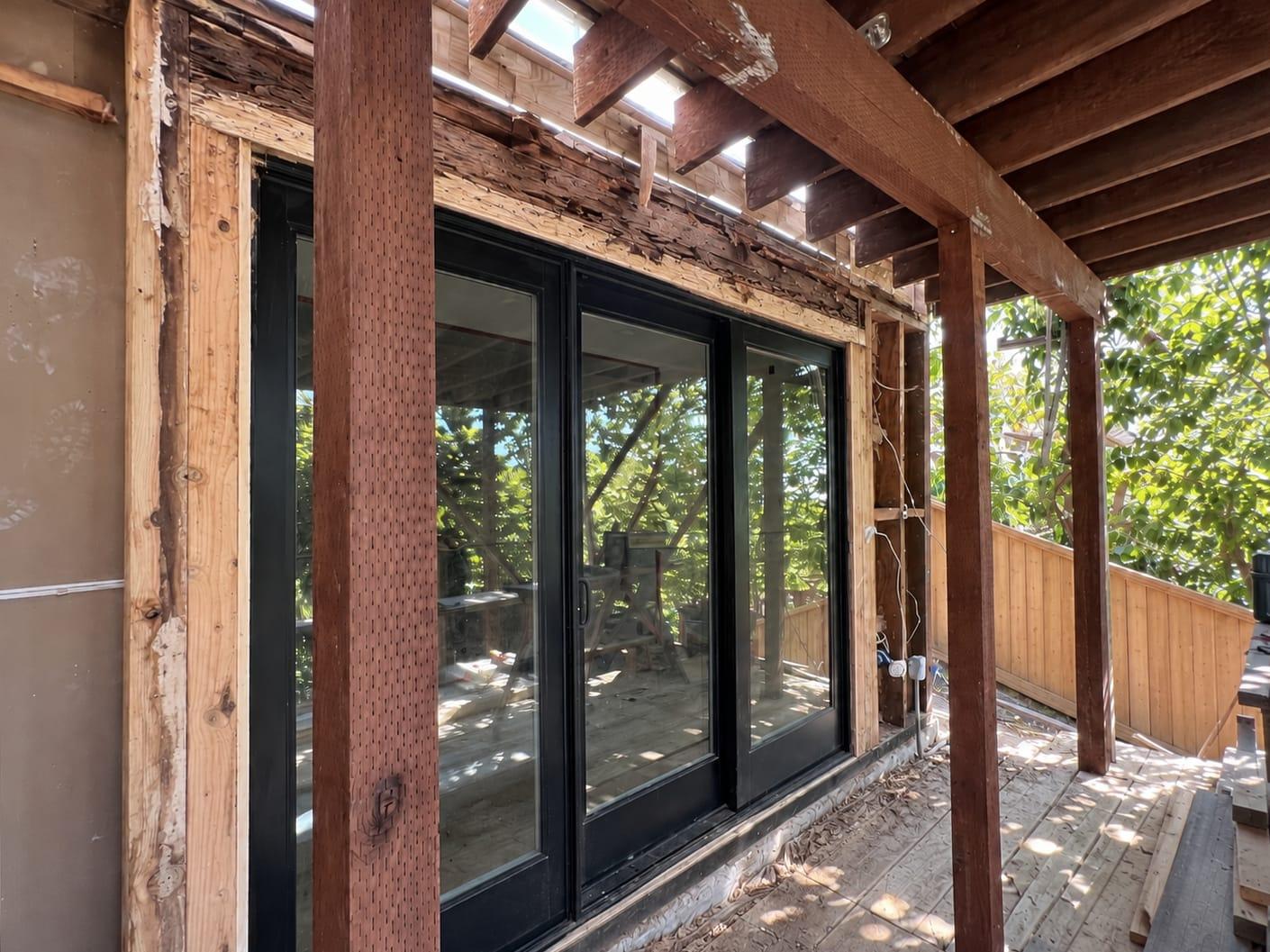 Rotted, shredded wood header exposed above a sliding glass door before structural repair by Gadget Construction